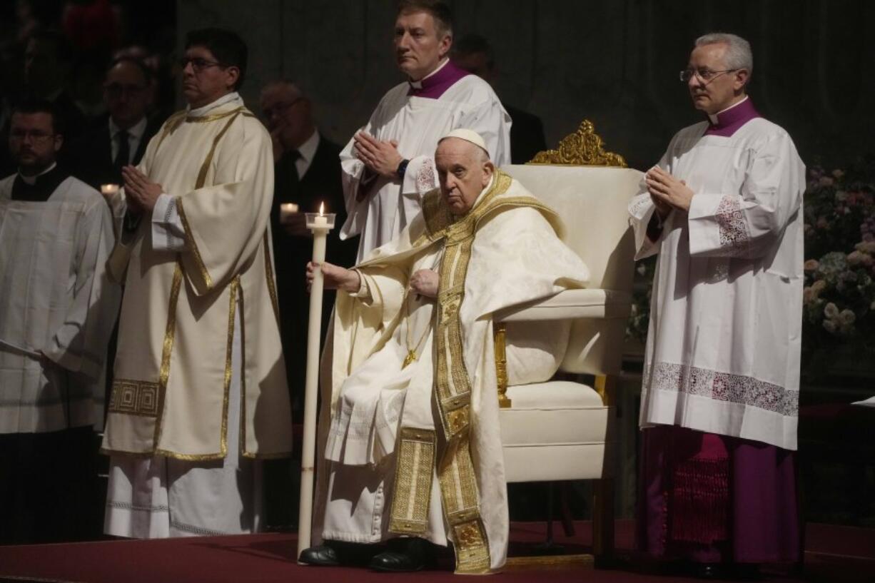 Pope Francis holds a Paschal candle as he presides over a Easter vigil ceremony in St. Peter's Basilica at the Vatican, Saturday, April 8, 2023.