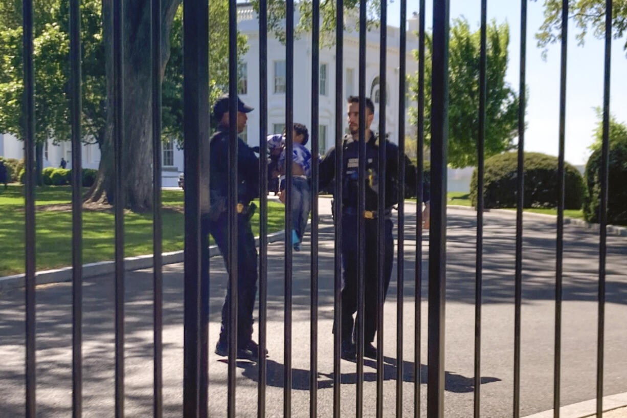 U.S. Secret Service uniformed division police officers carry a young child who crawled through the White House fence on Pennsylvania Avenue in Washington, Tuesday, April 18, 2023. The toddler earned the title of one of the tiniest White House intruders after he squeezed through the metal fencing on the north side of the executive mansion. Officers walked across the North Lawn to retrieve the child and reunite him with his parents on Pennsylvania Avenue.