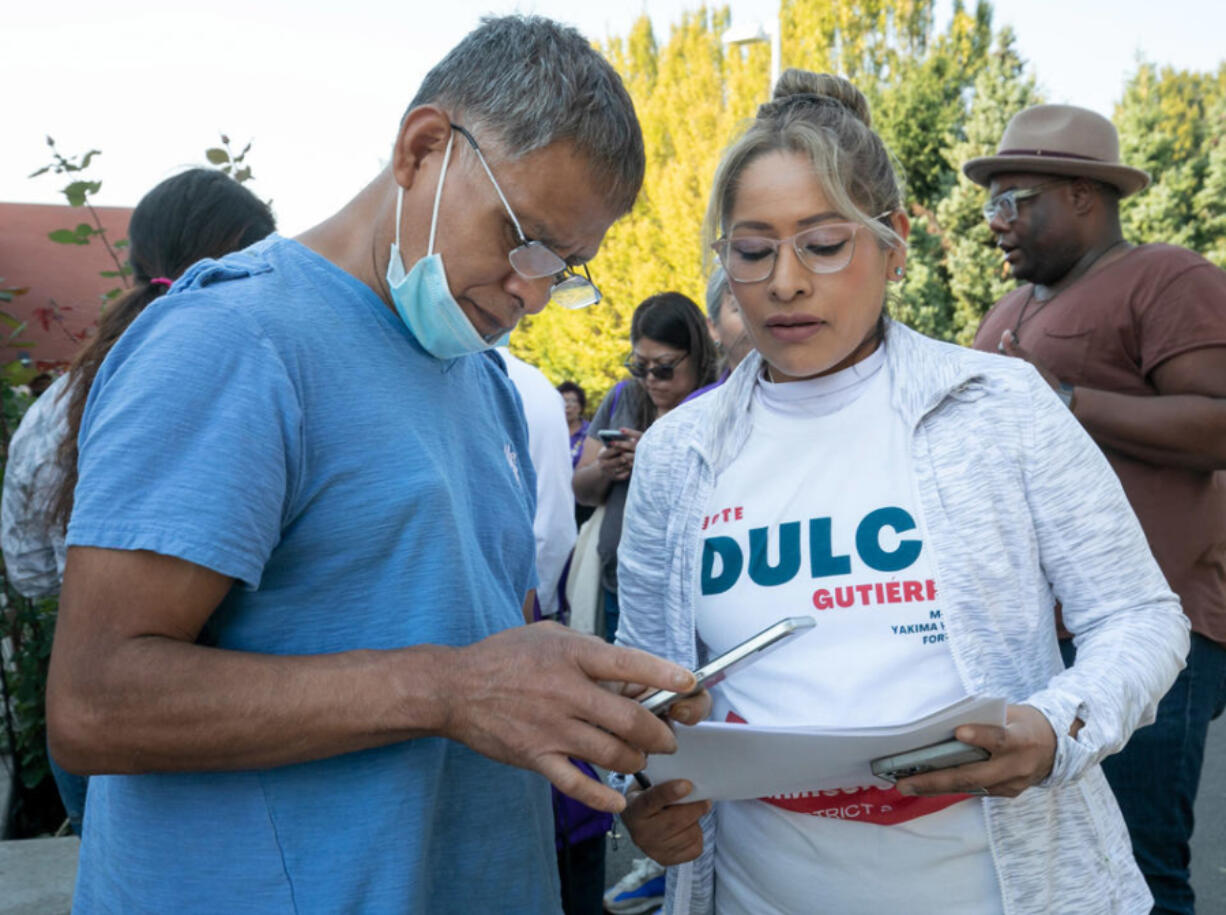 Rogelio Montes, left, takes a photo of the voter canvasing plan from Mary Lopez, before setting off door-knocking for Dulce Gutierrez, Democratic candidate for Yakima County Commissioner, District 2, on Sat. Oct. 15, 2022, in Yakima, Wash. Each volunteer was assigned between 30 to 50 homes with registered voters.