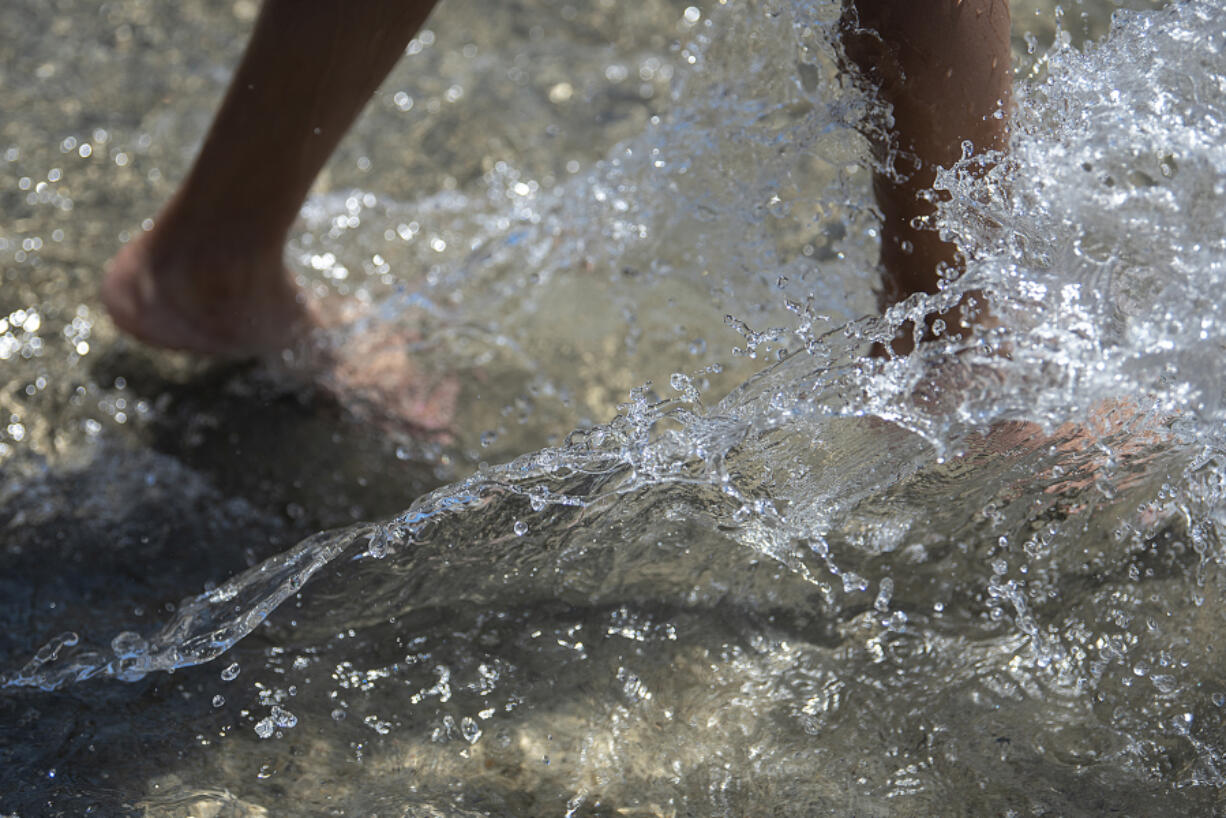 Residents cool off as they splash around in the water feature at The Waterfront Vancouver in 2022. The water feature will be open this weekend, when temperatures are expected to top 90 degrees.