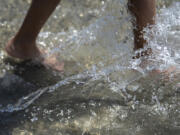 Residents cool off as they splash around in the water feature at The Waterfront Vancouver in 2022. The water feature will be open this weekend, when temperatures are expected to top 90 degrees.