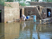 People remove bushes from their flooded houses in Sukkur, Pakistan, on Sept. 2.