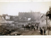 A firehose winds through a crowd of gawkers along Main Street at the edge of the Vancouver inferno of 1889. The firestorm gutted much of the city's downtown district, swallowing 26 buildings and damaging many more. After the torched real estate changed hands, the new owners rebuilt the four-block area in brick.