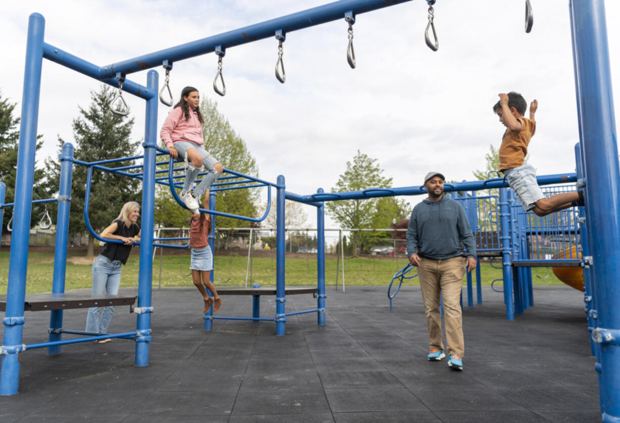 Filly Afenegus, second from right, watches as Noah Afenegus, 5, right, jump off of a playground structure while the rest of the family -- Tiffany, from left, Maia, 11, and Ella Afenegus, 9 -- watch at Felida Elementary School. Filly Afenegus recently stepped down as Columbia River's head boys soccer coach so he could spend more time with his family.