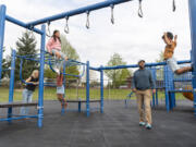Filly Afenegus, second from right, watches as Noah Afenegus, 5, right, jump off of a playground structure while the rest of the family -- Tiffany, from left, Maia, 11, and Ella Afenegus, 9 -- watch at Felida Elementary School. Filly Afenegus recently stepped down as Columbia River's head boys soccer coach so he could spend more time with his family.