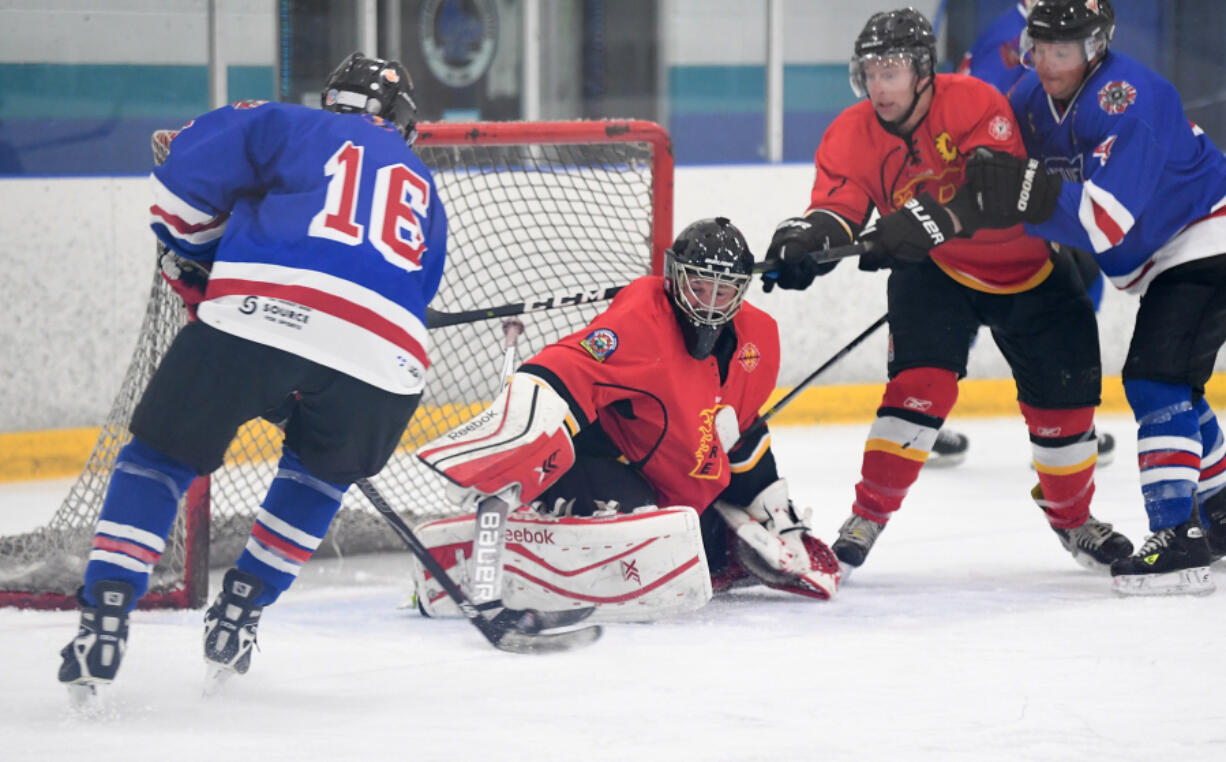 Portland Firefighters Hockey Club goalie Jim Pulito, center, with Columbia River Fire and Rescue, pokes the puck away from his net Friday during a game against the Vancouver, B.C., Firefighter's Hockey Club at Sherwood Ice Arena in Sherwood, Ore.( Taylor Balkom/The Columbian)