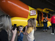 Melissa Stroud of Ridgefield, from left, pauses to snap a photo of her nieces, Mabel Gaussoin, 1, and her sister, Olivia, 3, as they test out their hot dog-shaped "weenie whistles" after visiting the Wienermobile at the Cascade Park Safeway on Tuesday afternoon.