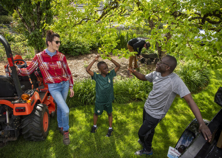 AnnMarie Taylor Haldeman, left, talks with neighbors Asnu, right, and Muktar Drammeh, 9, center, at the Taylor Family Farm. Haldeman said neighbors often come to help out on the farm, which is surrounded by homes.