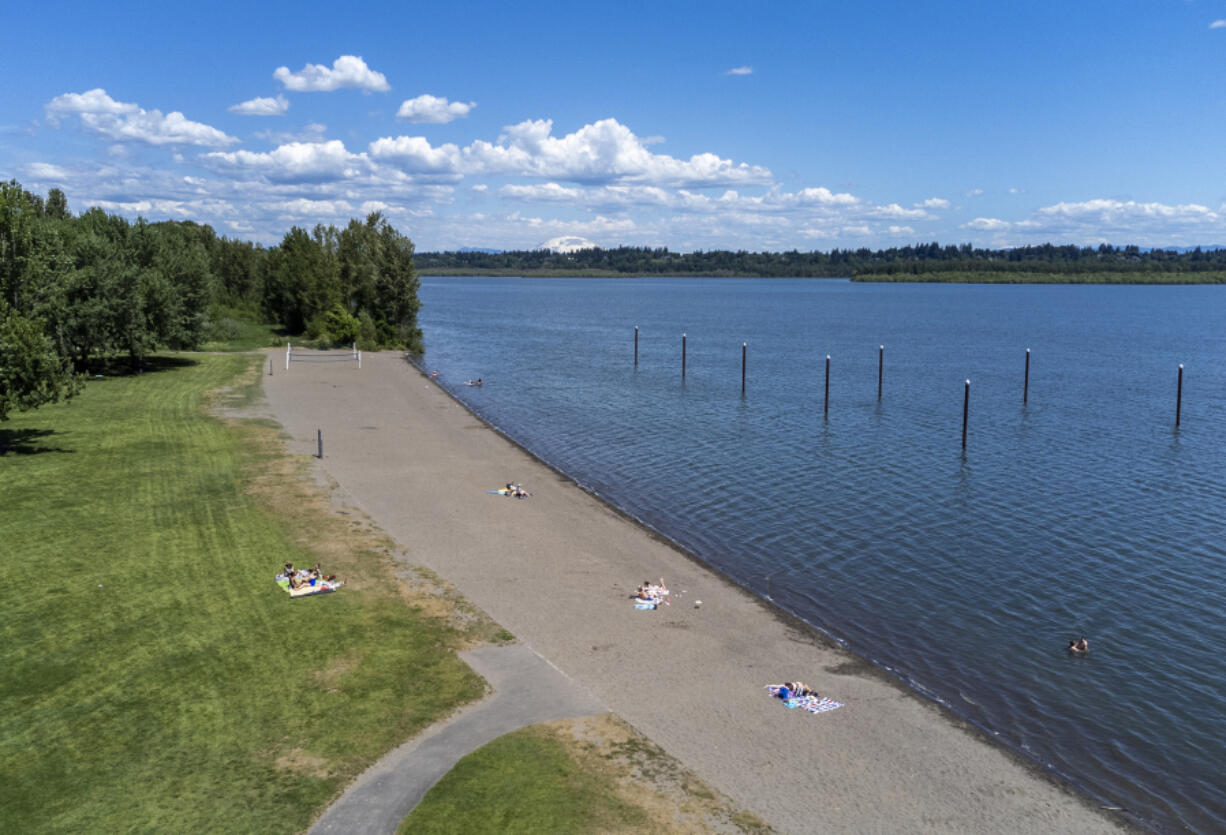 People sunbathe and play in the water Monday at Vancouver Lake. Temperatures are expected to remain in the mid- to upper 80s until the weekend.