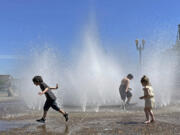 Children play in a fountain to cool off in downtown Portland, Ore., Friday, May 12, 2023. An early May heat wave this weekend could surpass daily records in parts of the Pacific Northwest and worsen wildfires already burning in western Canada, a historically temperate region that has grappled with scorching summer temperatures and unprecedented wildfires fueled by climate change in recent years.