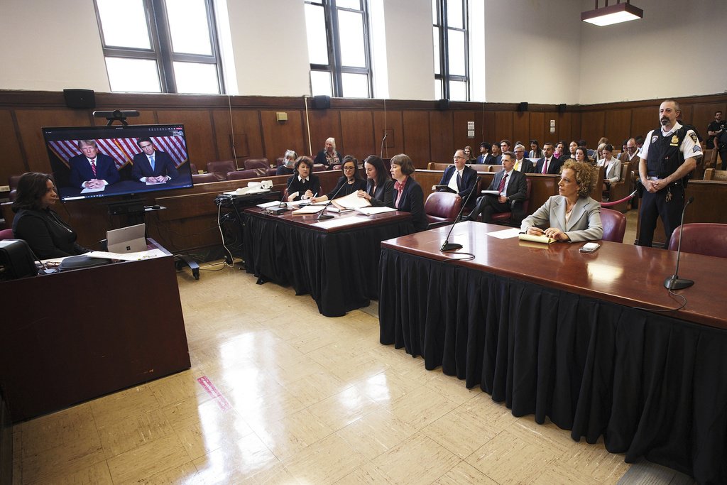 Former president Donald Trump, left on screen, and his attorney, Todd Blanche, right on screen, appear by video, as his other attorney Susan Necheles, right, looks on, before a hearing begins in Manhattan criminal court, in New York, Tuesday, May 23, 2023. Trump made a video appearance Tuesday in his New York criminal case, with the judge tentatively setting a trial date for late March of next year.