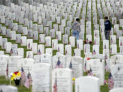 People walk among the headstones as they visit Section 60 at Arlington National Cemetery on Memorial Day, Monday, May 29, 2023, in Arlington, Va.