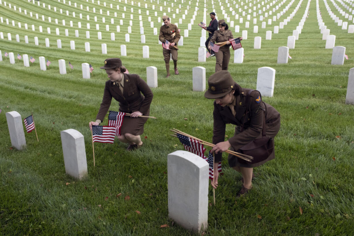 Shelby Anderson, left, and Carli Holland join other members from the Historical Unit of Southern California and other area scouts and volunteers to place flags in a salute to fallen soldiers at the Los Angeles National Cemetery on Saturday, May 27, 2023. The annual Memorial Day Flag Placement was held at Los Angeles National Cemetery where members of the Boy Scouts and other volunteers placed flags on the graves at the cemetery in West Los Angeles.