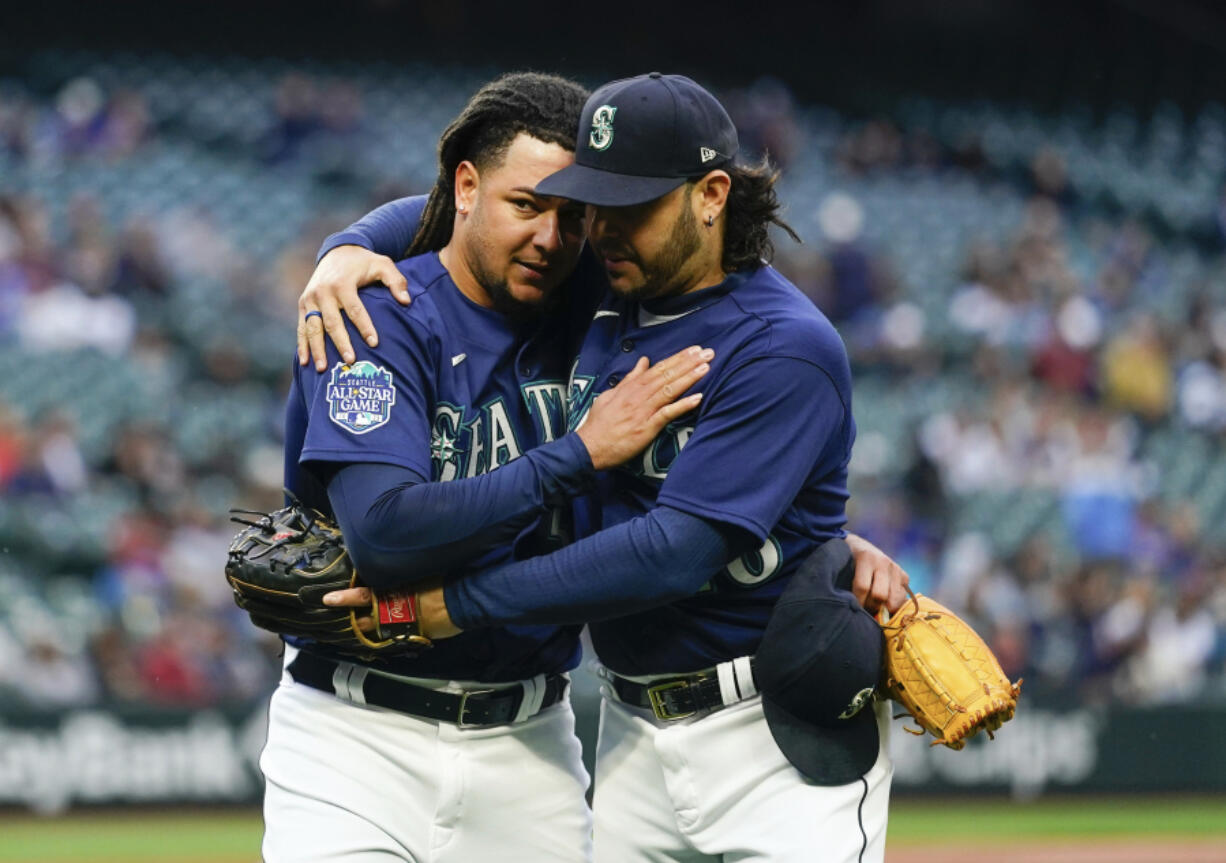 Seattle Mariners starting pitcher Luis Castillo, left, is hugged by third baseman Eugenio Suarez, right, as they walk back to the dugout after the fifth inning of a baseball game, against the Oakland Athletics, in which Castillo recorded 1,000th career strikeout Monday, May 22, 2023, in Seattle.