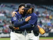 Seattle Mariners starting pitcher Luis Castillo, left, is hugged by third baseman Eugenio Suarez, right, as they walk back to the dugout after the fifth inning of a baseball game, against the Oakland Athletics, in which Castillo recorded 1,000th career strikeout Monday, May 22, 2023, in Seattle.