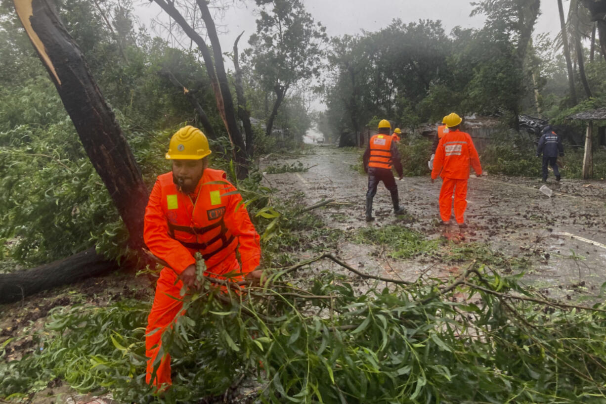 Rescue workers remove the fallen tress after a storm in Teknaf, near Cox's Bazar, Bangladesh, Sunday, May 14, 2023. Bangladesh and Myanmar braced Sunday as a severe cyclone started to hit coastal areas and authorities urged thousands of people in both countries to seek shelter.