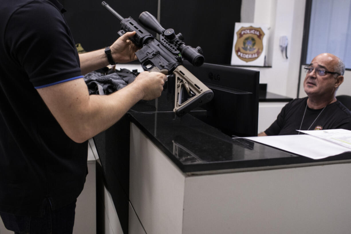 A gun owner holds a weapon as a police officer registers his firearms with the Federal Police on the deadline given by Brazil's government for gun registration with the National Weapons System of the Federal Police, in Rio de Janeiro, Brazil, Wednesday, April 3, 2023.