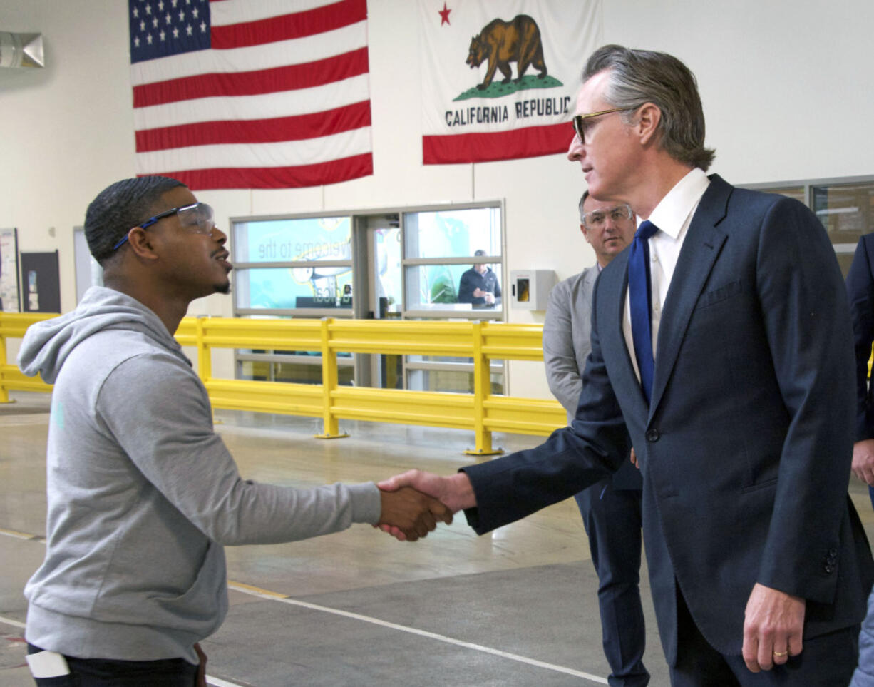 In this photo provided by the California Governor's Office, Governor Gavin Newsom, right, shakes hands with a MOXION employee Thursday, May 25, 2023, in Richmond, Calif. Newsom toured the battery manufacturing plant and touted his updated plan to ease the permitting process for new clean energy projects.