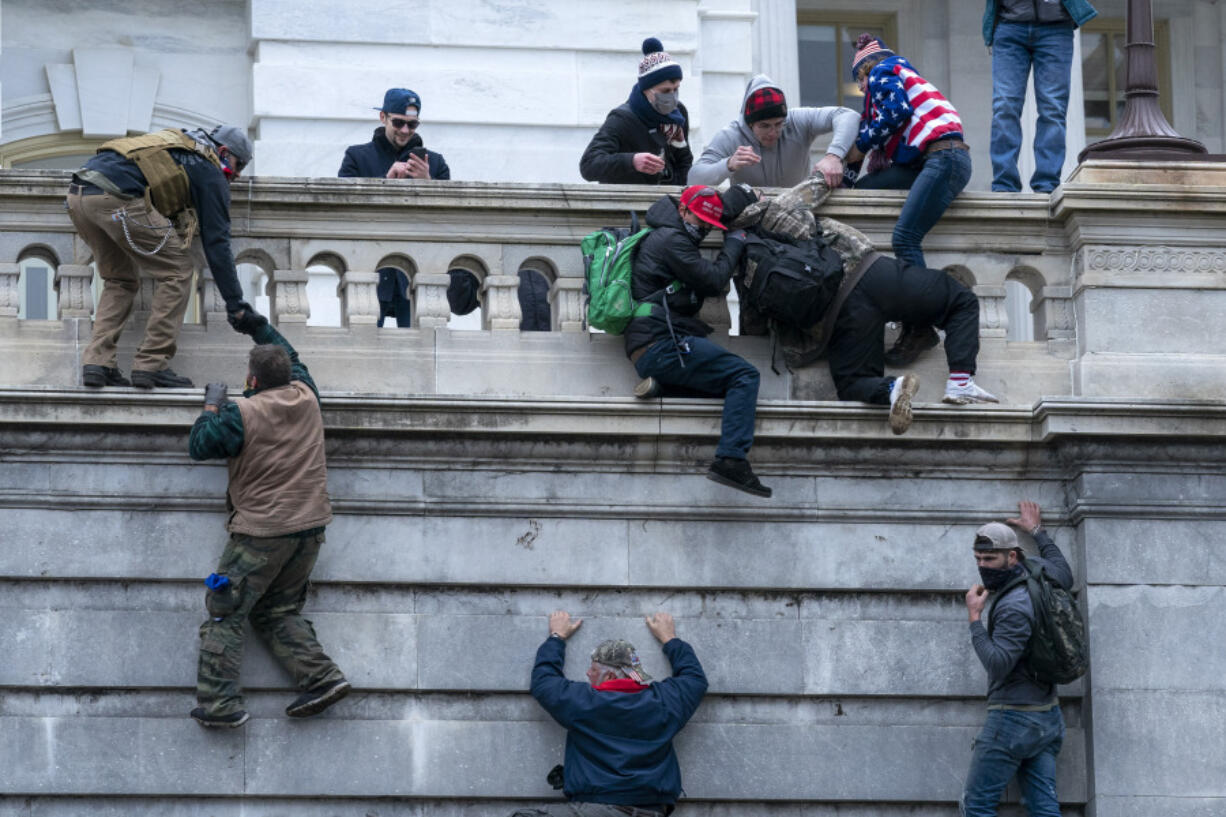 FILE - Rioters loyal to President Donald Trump climb the west wall of the the U.S. Capitol, Jan. 6, 2021, in Washington.