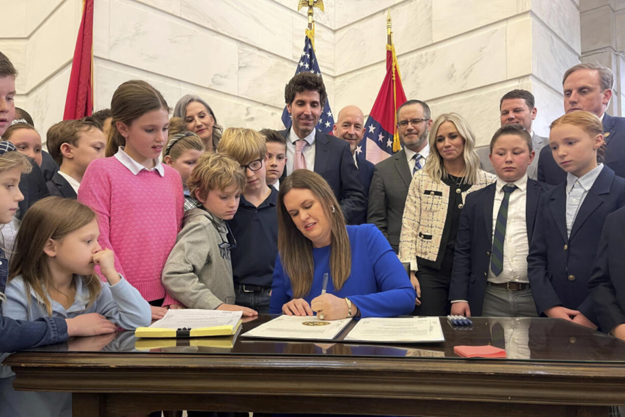 FILE - Arkansas Gov. Sarah Huckabee Sanders signs into law an education overhaul bill on Wednesday, March 8, 2023 at the state Capitol in Little Rock, Ark. As the federal government scrambles to crack down on surging child labor violations, some state lawmakers want to let children work longer hours and in more hazardous occupations. Republican Arkansas Gov. Sanders signed a law in March eliminating work permit requirements for children under 16, thereby also eliminating the age verification and parental consent required to obtain a permit.