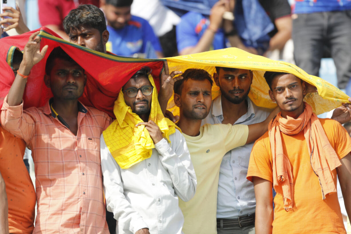 FILE - Cricket fans cover their heads with a long scarf to shield themselves from heat during an Indian Premier League (IPL) cricket match in Lucknow, India, April 22, 2023. A searing heat wave in parts of southern Asia in April this year was made at least 30 times more likely by climate change, according to a rapid study by international scientists released Wednesday, May 17.