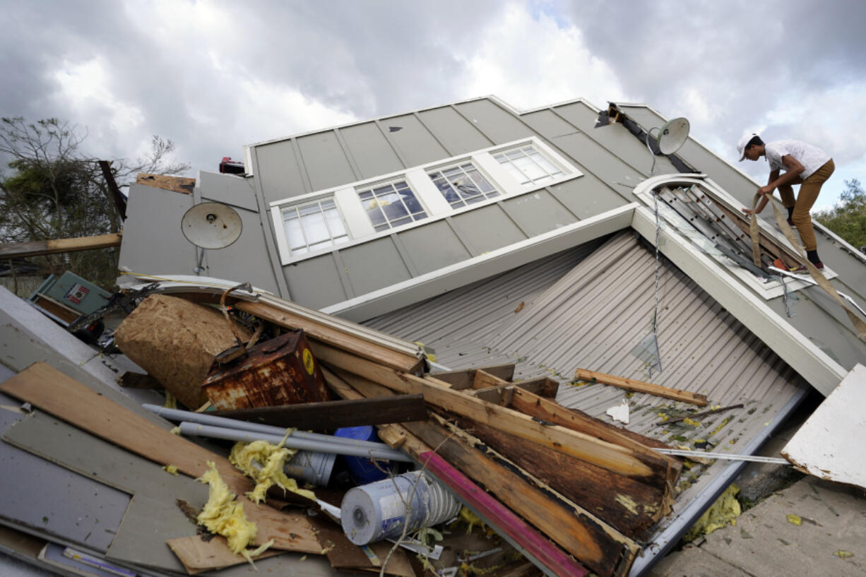 FILE - Jeremy Hodges climbs up the side of his family's destroyed storage unit in the aftermath of Hurricane Ida, Aug. 30, 2021, in Houma, La. National Oceanic and Atmospheric Administration on Thursday, May 25, 2023, announced its forecast for the 2023 hurricane season. (AP Photo/David J.