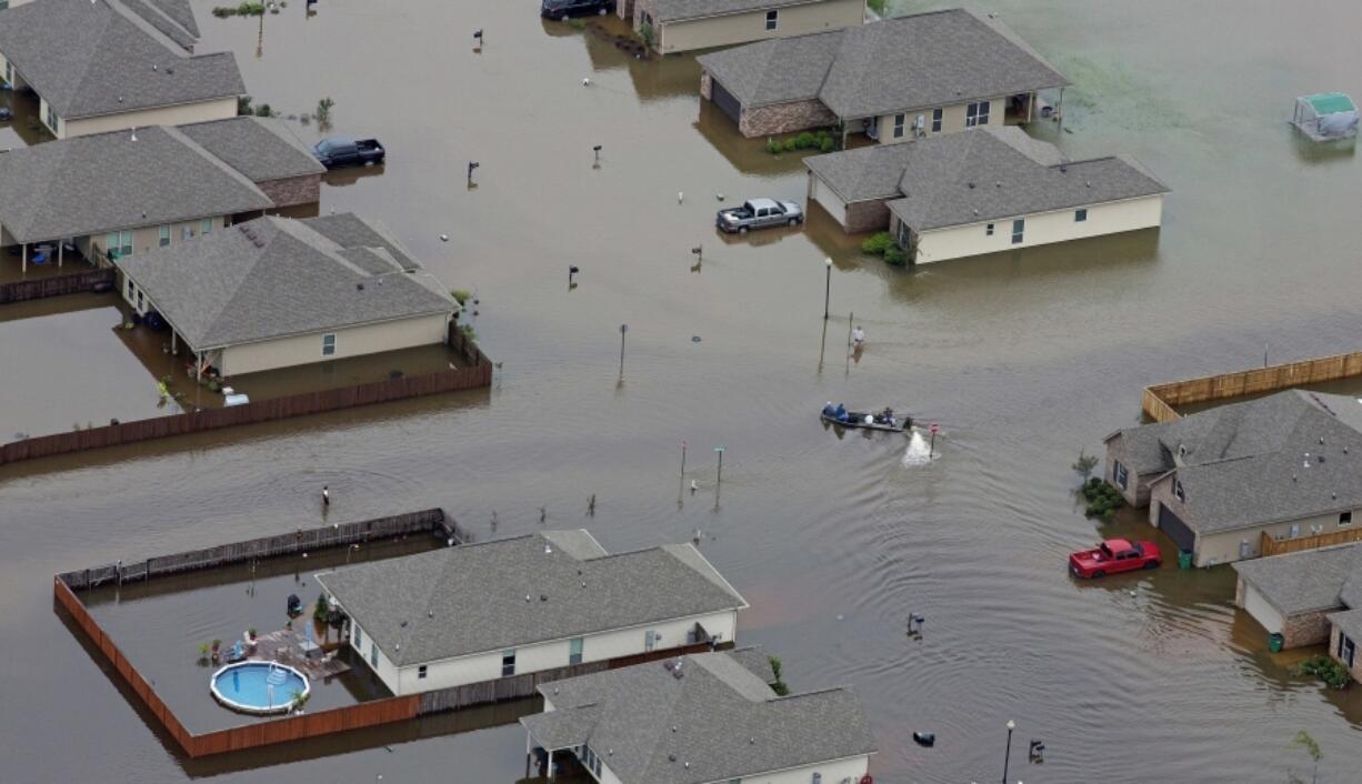 FILE- A boat motors between flooded homes after heavy rains inundating the region, in Hammond, La., on Aug. 13, 2016. A new study Thursday, May 18, 2023, finds the natural burst of El Nino warming that changes weather worldwide is far costlier with longer-lasting expenses than experts had thought, averaging trillions of dollars in damage.