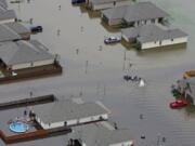 FILE- A boat motors between flooded homes after heavy rains inundating the region, in Hammond, La., on Aug. 13, 2016. A new study Thursday, May 18, 2023, finds the natural burst of El Nino warming that changes weather worldwide is far costlier with longer-lasting expenses than experts had thought, averaging trillions of dollars in damage.