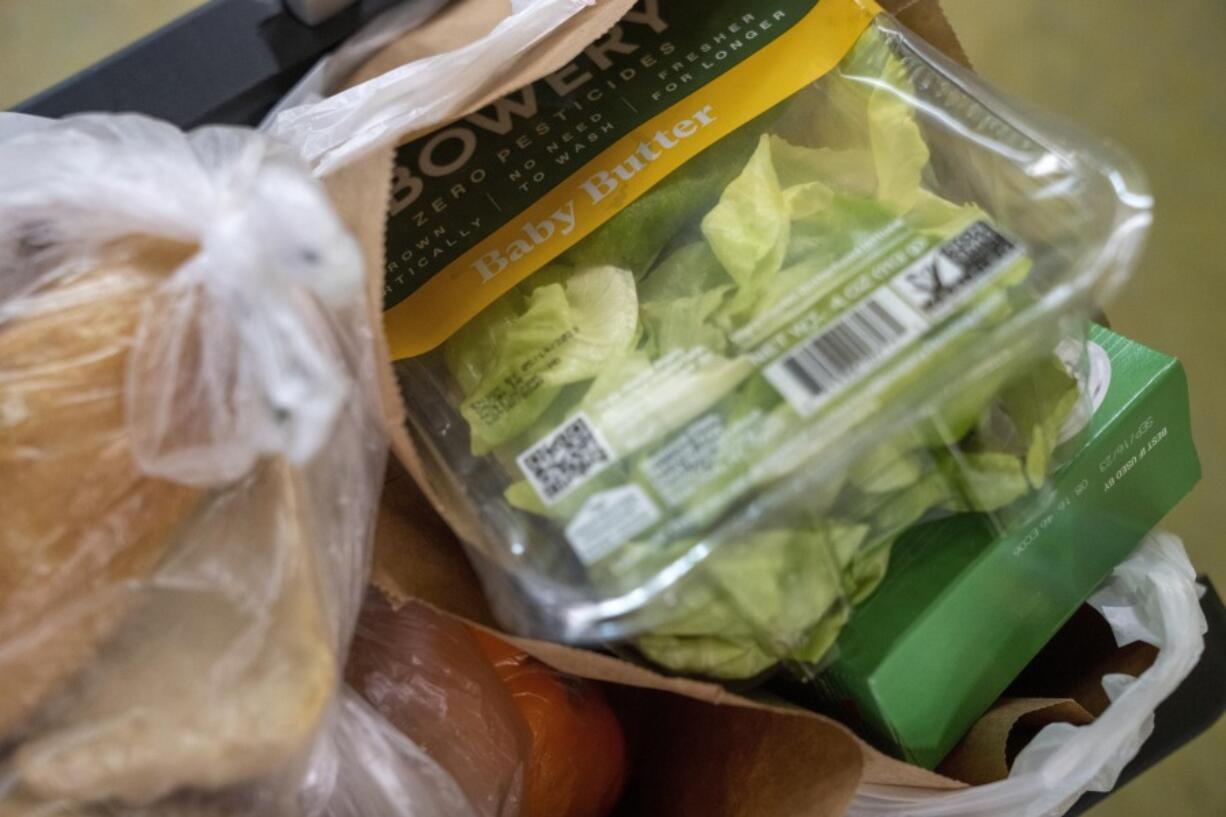 FILE - A mix of fresh and canned food items are placed in grocery bags at Bread for the City,  May 10, 2023, at the food pantry in Washington. Politicians in Washington may be offering assurance that the government will figure out a way to avert default, but around the country, economic anxiety is rising and some people already are adjusting their routines.