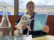 Ilana Minkoff checks out the menu with her dog JoJo Wigglebutt at a restaurant in San Francisco on Friday, May 5, 2023. Just in time for the summer dining season, the U.S. government has given its blessing to restaurants that want to allow pet dogs in their outdoor spaces.