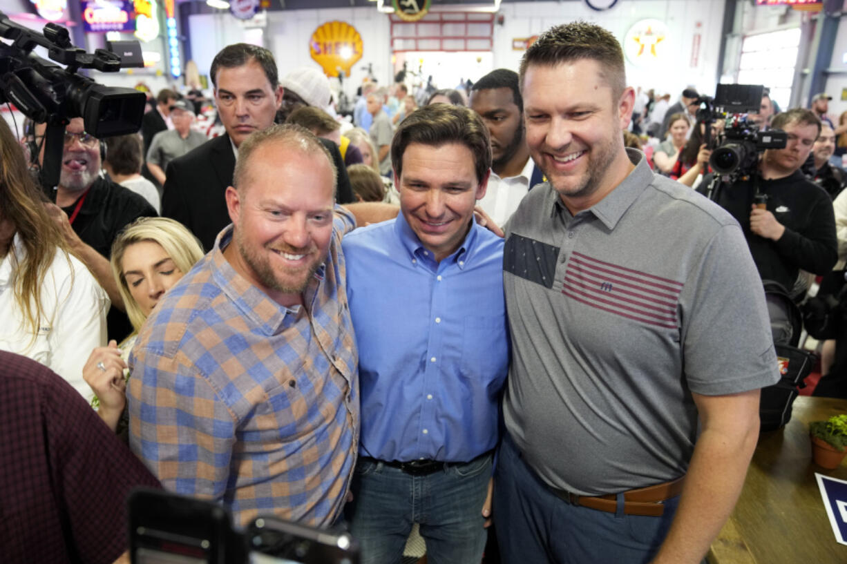 FILE - Florida Gov. Ron DeSantis, center, poses for a photo with audience members during a fundraising picnic forRep. Randy Feenstra, R-Iowa, May 13, 2023, in Sioux Center, Iowa. DeSantis is kicking off his presidential campaign in Iowa at the start of a busy week that will take him to 12 cities in three states as he tests his pitch as the most formidable Republican challenger to former President Donald Trump. (AP Photo/Charlie Neibergall.