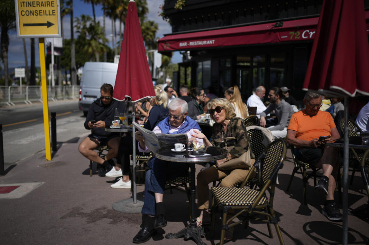 People sit at a cafe ahead of the Cannes film festival, in Cannes, southern France, Sunday, May 14, 2023. The 76th edition of the film festival runs from May 16 until May 27.