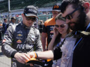 Fan-favorite Pato O'Ward signs an autograph during a recent Indianapolis 500 practice session. His jersey sales are tops in IndyCar, nearly 35% higher than the next driver. His collective merchandise offerings supply draws the highest revenue of any driver retail line.