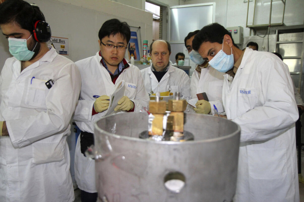 FILE - International Atomic Energy Agency inspectors and Iranian technicians prepare to cut the connections between the twin cascades for 20% uranium enrichment at the Natanz nuclear site near Natanz, Iran, Jan. 20, 2014. A new underground facility at the Natanz enrichment site may put centrifuges beyond the range of a massive so-called "bunker buster" bomb earlier developed by the U.S. military, according experts and satellite photos analyzed by The Associated Press in May 2023.