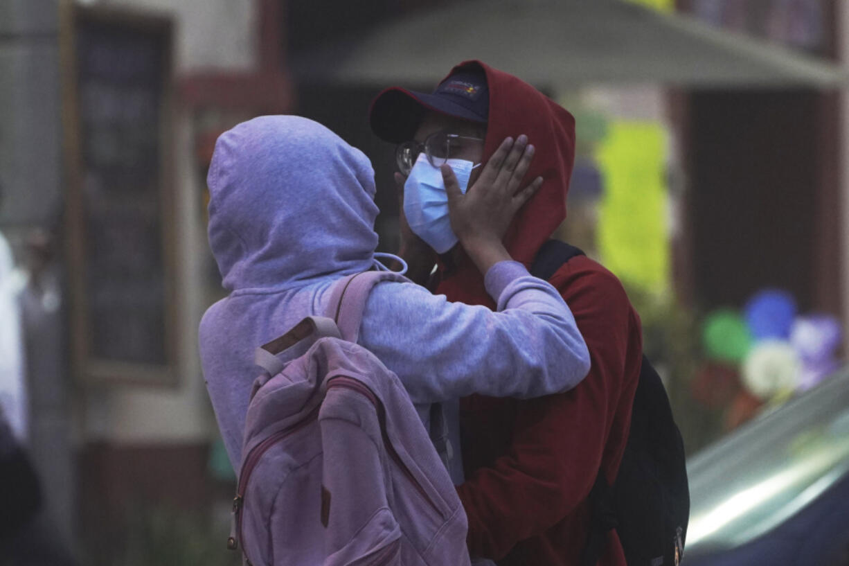 A couple wearing hoodies and masks to protect themselves from the ash fall of the Popocat?petl volcano embraces in Atlixco, Mexico, Monday, May 22, 2023. The volcano's activity has increased over the past week. Evacuations have not been ordered, but authorities are preparing for that scenario and telling people to stay out of 7.5-mile (12-kilometer) radius around the peak.