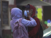 A couple wearing hoodies and masks to protect themselves from the ash fall of the Popocat?petl volcano embraces in Atlixco, Mexico, Monday, May 22, 2023. The volcano's activity has increased over the past week. Evacuations have not been ordered, but authorities are preparing for that scenario and telling people to stay out of 7.5-mile (12-kilometer) radius around the peak.