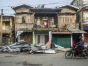 A local rides motorbike past damaged buildings after Cyclone Mocha in Sittwe township, Rakhine State, Myanmar, Monday, May 15, 2023. Rescuers on Monday evacuated about 1,000 people trapped by seawater 3.6 meters (12 feet) deep along western Myanmar's coast after the powerful cyclone injured hundreds and cut off communications.