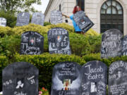 FILE - Jayde Newton helps to set up cardboard gravestones with the names of victims of opioid abuse outside the courthouse where the Purdue Pharma bankruptcy is taking place in White Plains, N.Y., on Aug. 9, 2021. A three-judge panel of the 2nd U.S. Circuit Court of Appeals in New York on Tuesday, May 30  overturned a lower court's 2021 ruling that found bankruptcy courts did not have the authority to protect members of the Sackler family who own the company and who have not filed for bankruptcy protection from lawsuits.