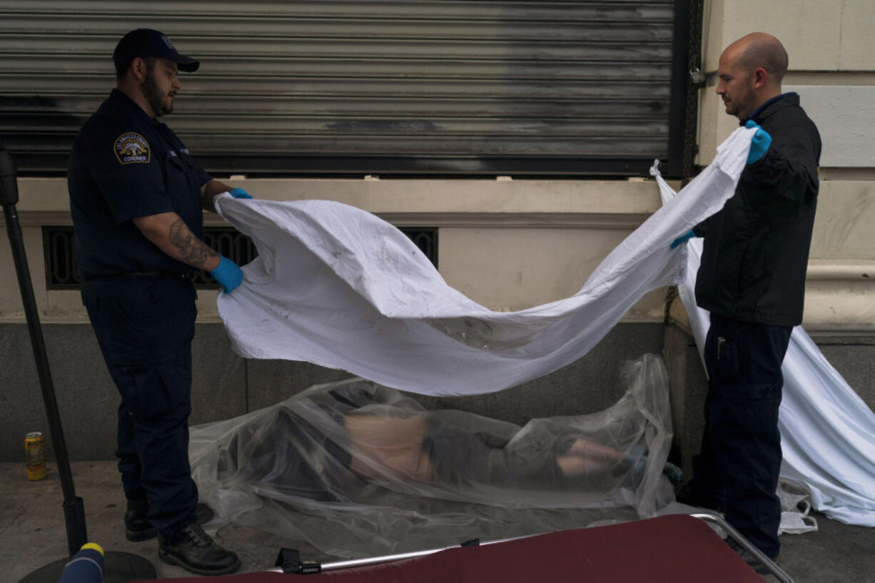 FILE - Forensic assistant Laurentiu Bigu, left, and investigator Ryan Parraz from the Los Angeles County coroner's office cover the body of a homeless man found dead on a sidewalk in Los Angeles on April 18, 2022. The 60-year-old man died from the effects of methamphetamine, according to his autopsy report. Drug overdose deaths in the U.S. went up slightly in 2022 after two big leaps during the pandemic. (AP Photo/Jae C.