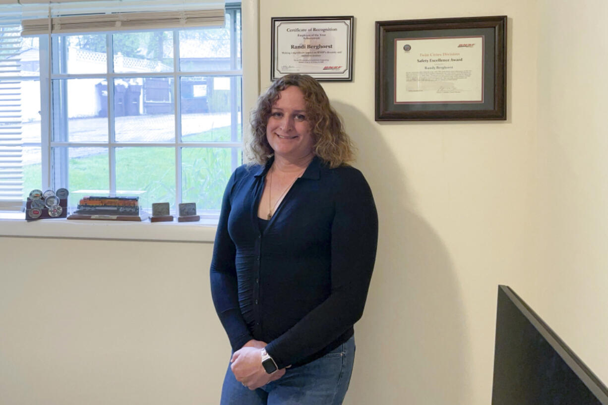 Former longtime BNSF worker Randi Berghorst poses in front of the employee of the year plaque the railroad gave her in recognition of her work supporting LGBTQ+ workers, at her apartment in Woodstock, Ill., in May 2023. Berghorst says that after being promoted regularly earlier in her career she was denied advancement opportunities after her gender transition and could hardly get an interview.