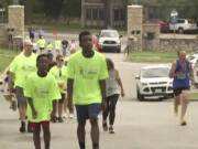 In this image made from video provided by KCTV, Ralph Yarl, center, wearing a bright green "Team Ralph" shirt, participates in a walk in an event called "Going the Distance for Brain Injury" at Loose Park in Kansas City, Mo., Monday, May 29, 2023. Yarl, a Black teenager who was shot in the head and arm in April after mistakenly ringing the wrong doorbell, walked at the brain injury awareness event Monday in his first major public appearance since the shooting.