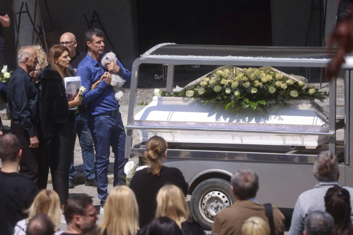 Parents of Ema Kobiljski, 13, mourn during the funeral procession at the central cemetery in Belgrade, Serbia, Saturday, May 6, 2023. Her schoolmate, a 13-year-old boy, on Wednesday, used his father's guns to kill eight fellow students and a guard.