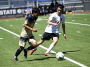 Sam Soto of Seton Catholic (left) dribbles the ball past Seattle Academy's Ben Cady during Seton Catholic's 4-0 loss to Seattle Academy in the 1A boys soccer state semifinal at Renton Memorial Stadium on Friday, May 26, 2023.