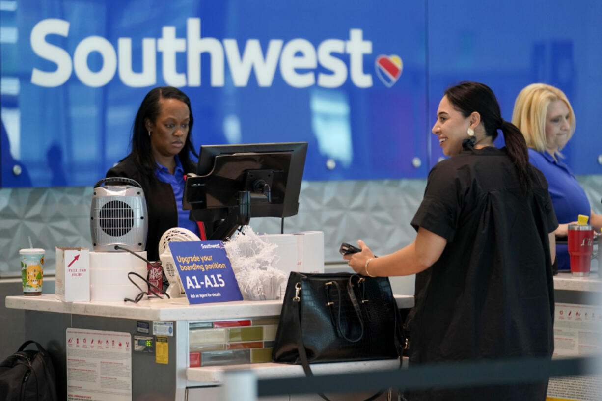 A Southwest airlines customer service representative, left, assists a traveler at the ticketing counter at Love Field airport, Friday, May 19, 2023, in Dallas.