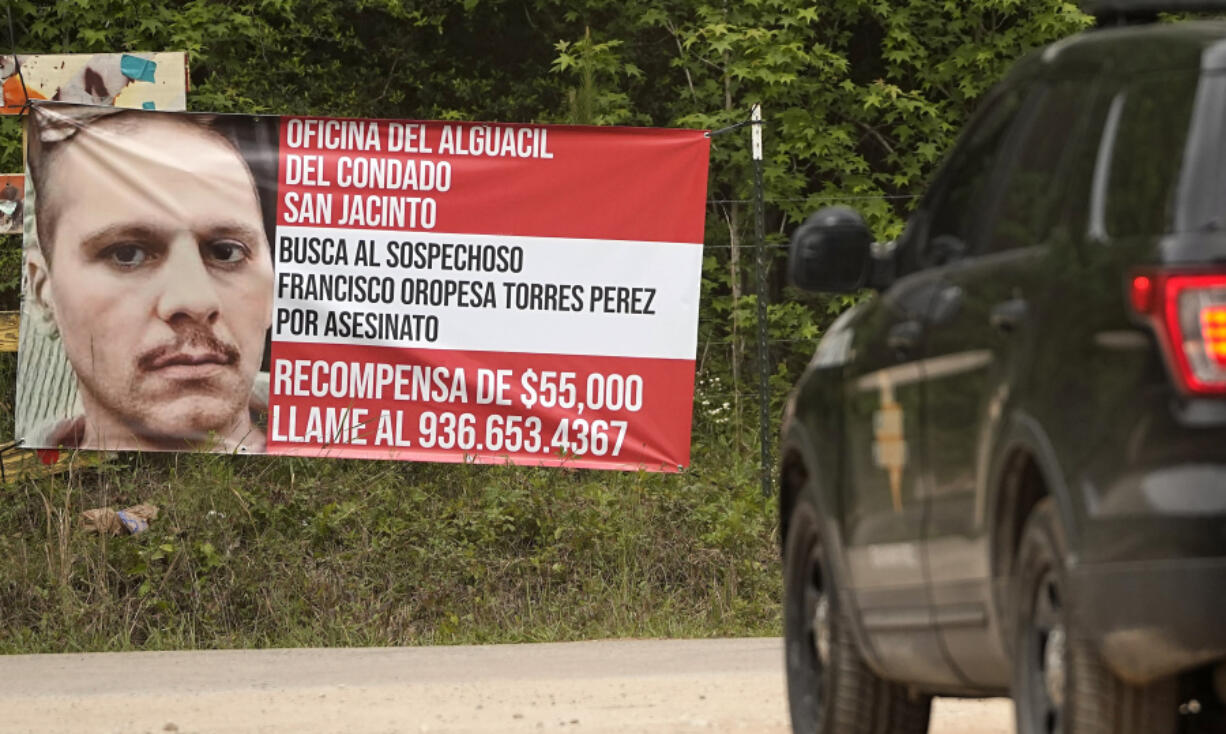 A state trooper vehicle passes a posted wanted sign for a mass shooting suspect Tuesday, May 2, 2023, in the neighborhood where the shooting occurred Friday, in Cleveland, Texas. The search for the suspected gunman who allegedly shot five of his neighbors, including a child, after they asked him to stop firing off rounds in his yard stretched into a fourth day Tuesday. (AP Photo/David J.