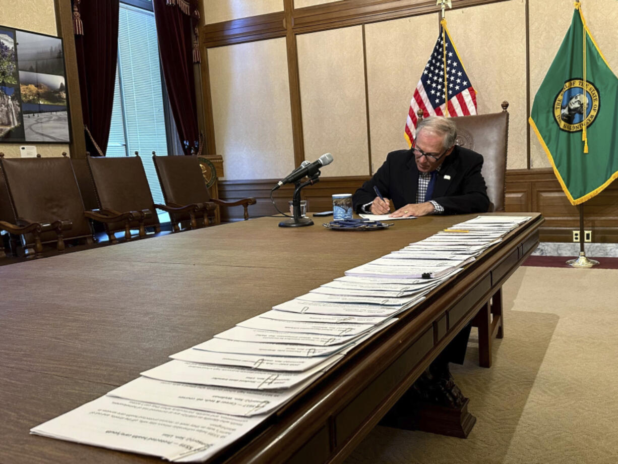 Washington Gov. Jay Inslee signs bills at the Washington State Capitol, Tuesday, May 9, 2023, in Olympia, Wash. One of those bills was Senate Bill 5599, which was designed to protect young people seeking reproductive health services or gender-affirming care.