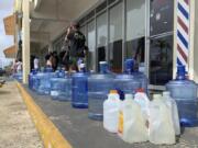 Numerous containers line the sidewalk outside the Wellness Water & Ice store in Yigo, Guam, as island residents make preparations for possible inclement weather on Sunday, May 21, 2023. Guam's governor is urging residents to stay home and is warning the island could take a direct hit from Typhoon Mawar. The storm is strengthening on its path toward the U.S. territory in the Pacific.