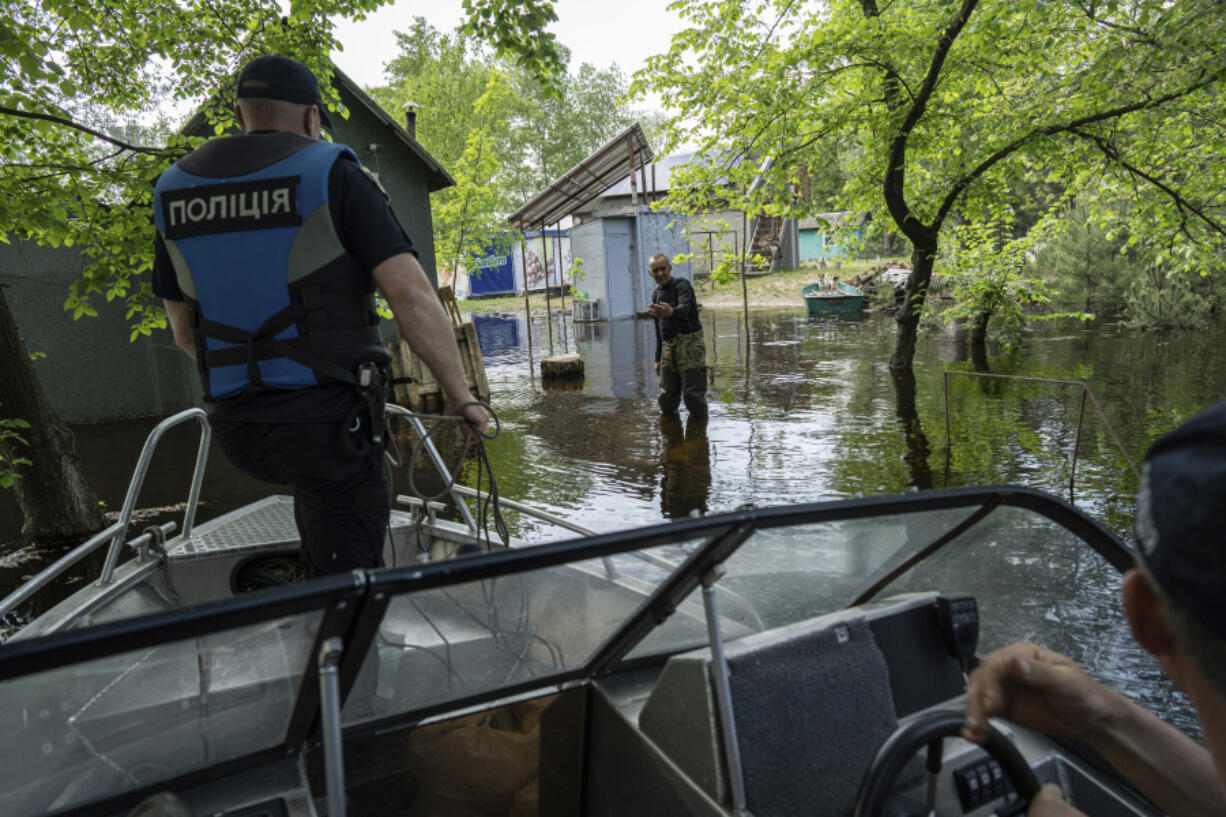 Ihor Medyunov, a local hunter greats police officers at the his flooded courtyard in the island of Kakhovka reservoir on Dnipro river near Lysohirka, Ukraine, Thursday, May 18, 2023. Damage that has gone unrepaired for months at a Russian-occupied dam is causing dangerously high water levels along a reservoir in southern Ukraine.