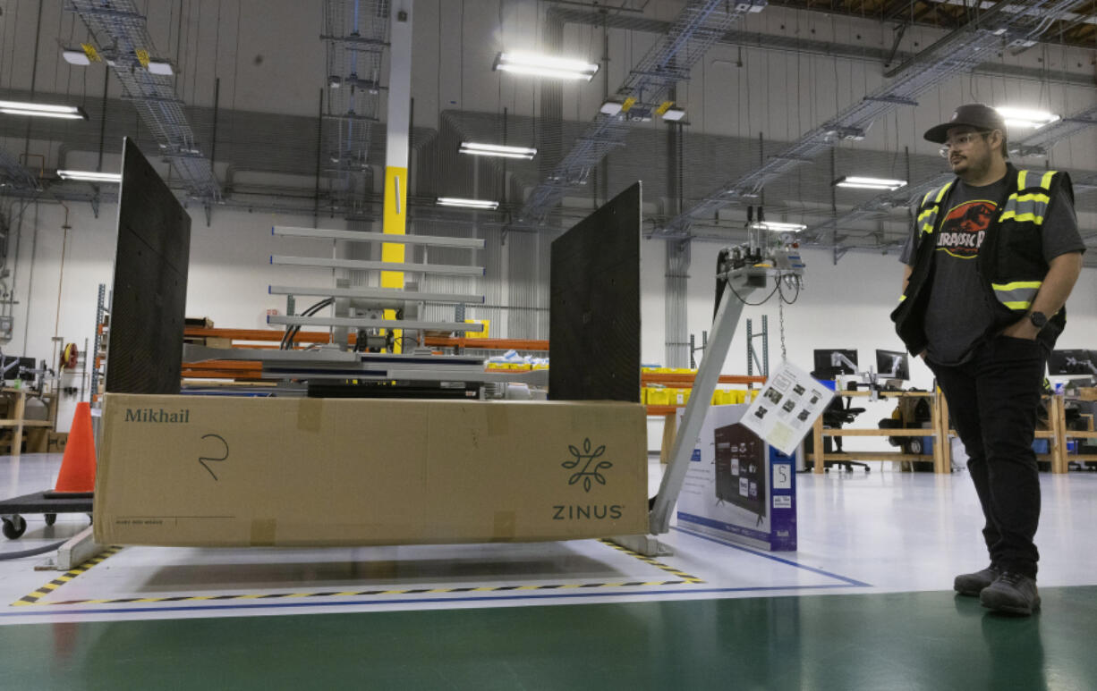 Marcos Trevizo, a lab tech in Amazon???s sustainable packaging lab in Sumner, uses a machine to squeeze a package to check the durability of the packaging that is holding merchandise Monday, May 22, 2023. (Ellen M.