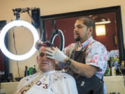Chico's Classic Barbershop owner Raul Barasa, right, cuts the hair of Mike Tomasello, of Vancouver, on May 24. Barasa started cutting hair on a volunteer basis, then turned it into an occupation.